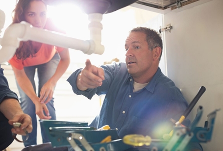 plumber pointing at pipe under sink